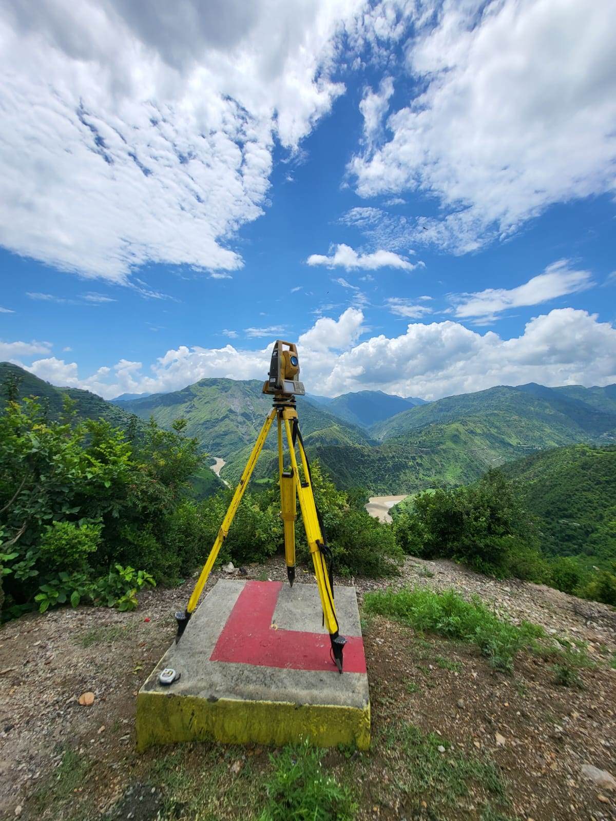 Total station mounted on a concrete control pillar overlooking a Himalayan river valley