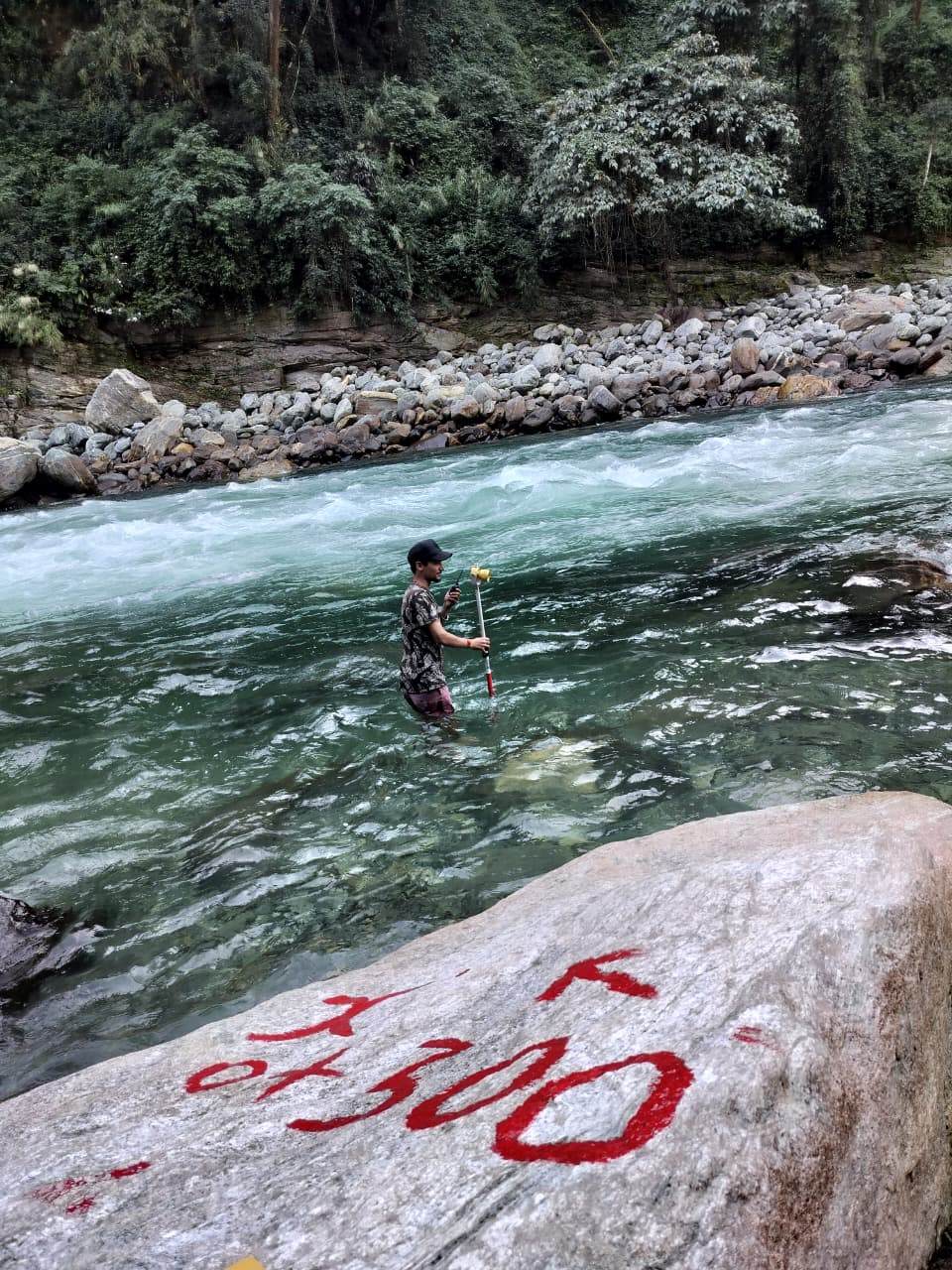 Surveyor taking a staff reading mid-stream at chainage 0+300